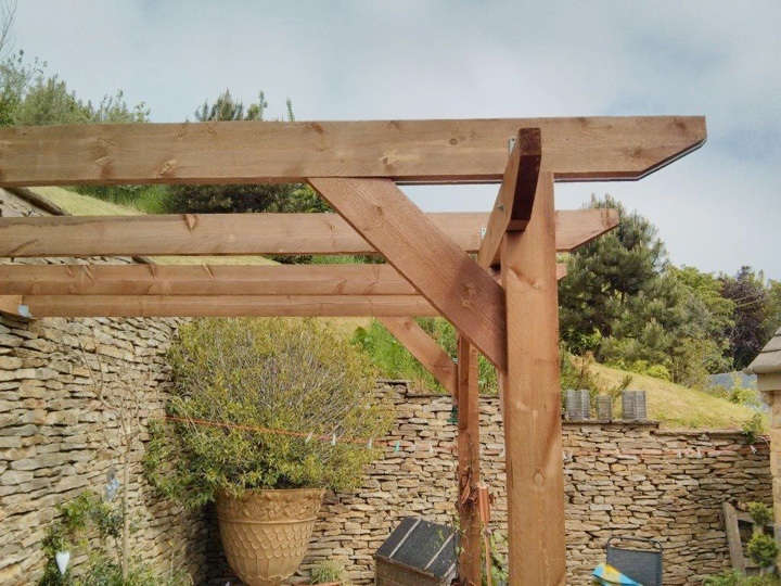 A close up of a lean-to pergola, with hills in the distance