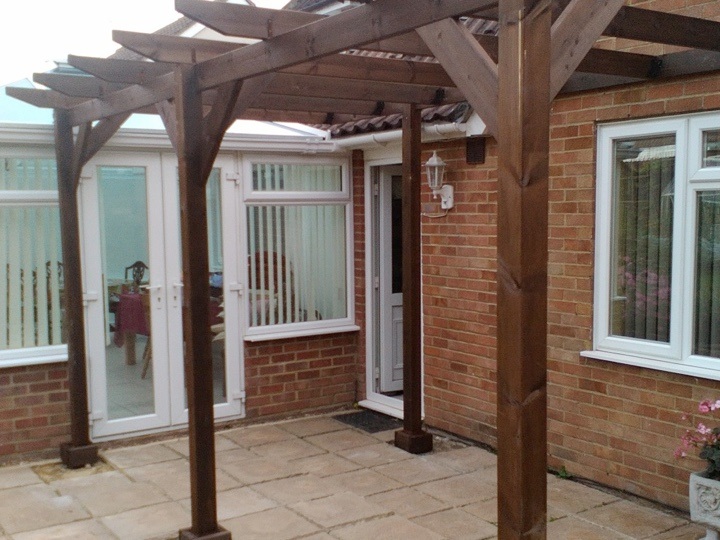 A lean-to pergola built against a customers house, and stained with a dark wood stained